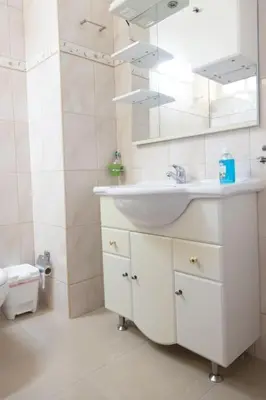 a white bathroom with a sink and a toilet at 3 bedroom apt, FREE WIFI & AC, Cidadela - LCGR in Praia