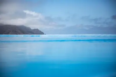 a large body of blue water with mountains in the background at RM Green Hotel in Lombo Branco