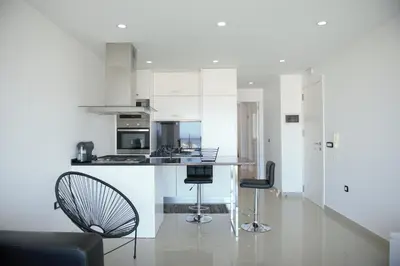 a kitchen with white cabinets and a counter and chairs at Duarte Apartments - Vista in Mindelo