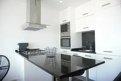 a white kitchen with a black counter top at Duarte Apartments - Vista in Mindelo