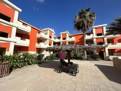 an umbrella and benches in front of a building at Zen House Morabeza in Santa Maria