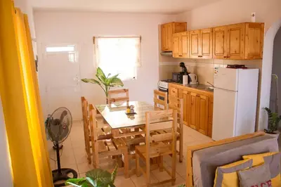 a kitchen with a table and chairs and a refrigerator at Cosy & Relax Yellow House 5mn walk from the beach! in Calheta Do Maio