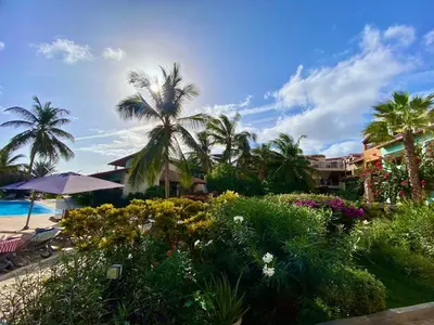 a garden with flowers and palm trees next to a beach at Porto Antigo 2 - By Bobbywashere in Santa Maria