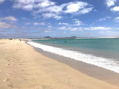 a beach with people flying kites in the water at Blu Shell - Ca' Greta in Sal Rei