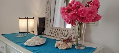 a table with a vase with pink flowers on it at Blu Shell - Ca' Greta in Sal Rei