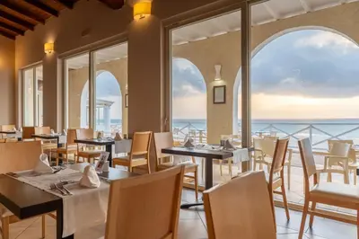 a restaurant with tables and chairs and a view of the ocean at VOI Praia de Chaves Resort in Sal Rei