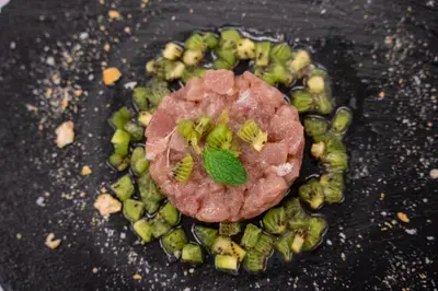 a piece of meat and vegetables on a frying pan at VOI Praia de Chaves Resort in Sal Rei