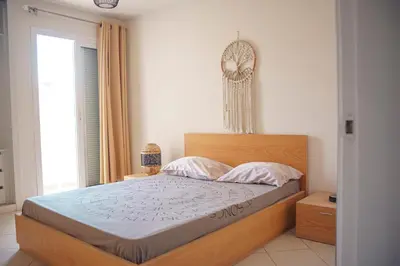 a bedroom with a bed with a wooden headboard and a window at 2 bdr cozy beachside apartment, Copacabana - LCGR in Mindelo