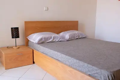 a bed with a wooden headboard and two pillows at 2 bdr cozy beachside apartment, Copacabana - LCGR in Mindelo