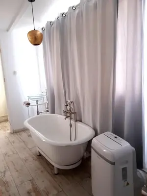 a white bathroom with a tub and a toilet at As Hortênsias in Mindelo