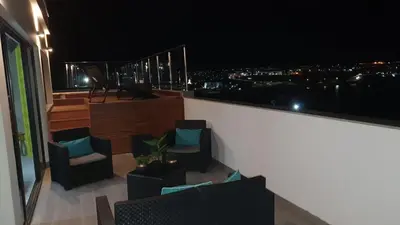 a balcony with chairs and a view of the city at night at Résidence Cazino Apartamentos in Praia