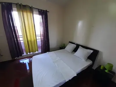 a bedroom with a bed with white sheets and two windows at Tarrafal House in Tarrafal