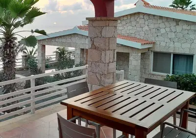 a wooden table and chairs on a balcony with a house at Villa Lagosta Stella Maris Exclusive in Vila do Maio