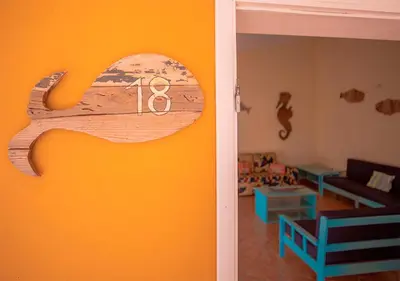 a living room with an orange wall with a sign on it at Villa Atum. Stella Maris Exclusive in Vila do Maio