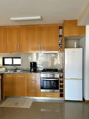 a kitchen with wooden cabinets and a white refrigerator at Casa So Morabeza in Mindelo
