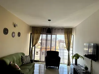 a living room with a green couch and a large window at Casa So Morabeza in Mindelo