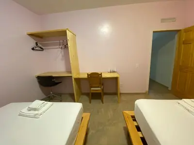 a room with two beds and a desk and a table at Spencer Residencial APARTAMENTOS in Praia