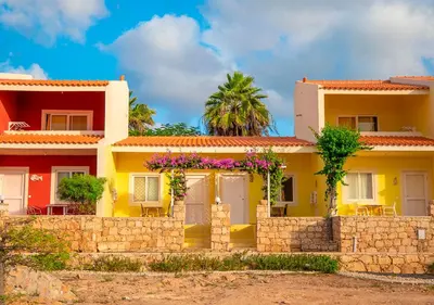 a yellow house with flowers on a stone wall at Appartamento Buzio. Stella Maris Exclusive in Vila do Maio