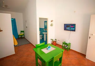 a room with a green table and a bathroom at Appartamento Buzio. Stella Maris Exclusive in Vila do Maio