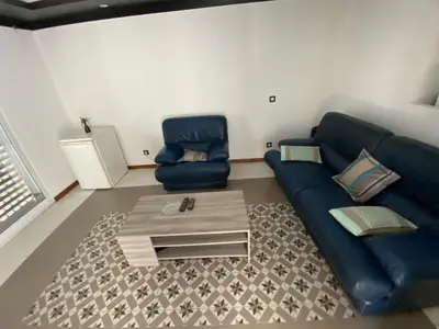 a living room with a blue couch and two chairs at Casa Chiquinha in Ribeira da Prata
