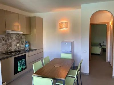 a kitchen with a wooden table and green chairs at Djadsal Moradias in Santa Maria