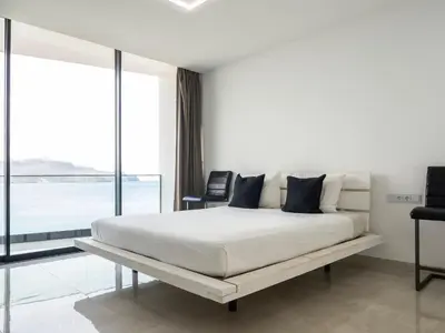 a white bedroom with a large bed and a large window at Apartment Sunset in Mindelo