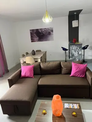 a living room with a brown couch and pink pillows at Apartamentos Santiago - Tarrafal in Tarrafal
