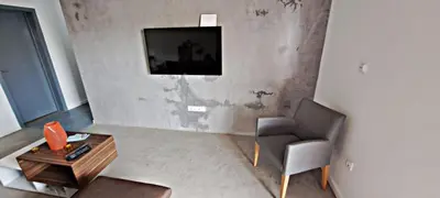 a living room with a chair and a television on a wall at Apartamentos Santiago - Tarrafal in Tarrafal